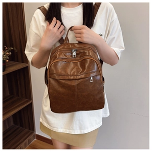 Detail of soft brown leather backpack with multiple zipper compartments and carry handle