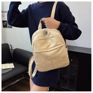 Detail of minimalist beige PU leather backpack with silver metallic zippers and front pocket