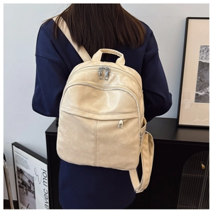 Model wearing a beige leather texture backpack with front zipper pocket and side slots