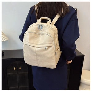 Detailed view of cream PU leather backpack featuring functional multi-pocket design and soft texture