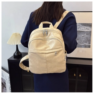 Detail of cream multi-functional backpack showing smooth texture and silver metal zippers