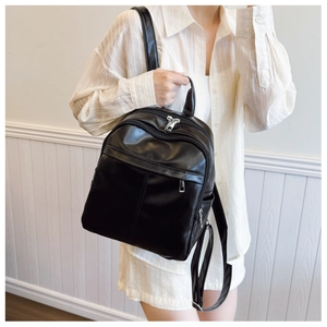 Detailed view of black PU leather backpack with silver zippers and smooth texture