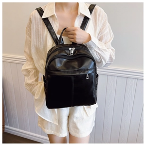 Detail of minimalist black PU leather backpack with vertical stitching and silver hardware