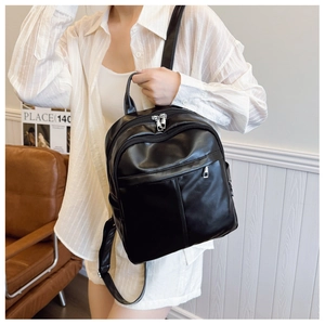 Detailed view of the shiny black PU leather backpack with zippers on a model