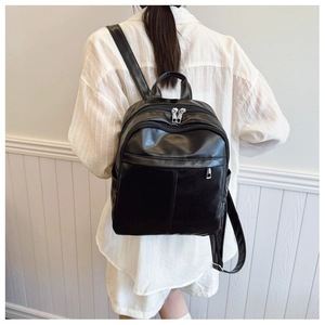 Detail of a black leather backpack with multiple zip pockets and adjustable straps