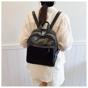 Rear view of model wearing a glossy black PU leather backpack with silver zippers