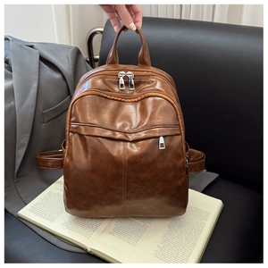 Detail view of brown faux leather backpack on vintage books with focus on zipper texture