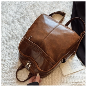 Flat lay of brown vintage PU leather backpack with multiple zippers and side pockets