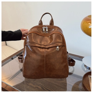 Detail of brown leather multi-functional backpack with multiple pockets on a wooden table