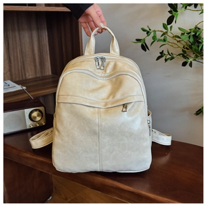Detailed view of beige PU leather backpack with vintage texture and multiple zip pockets