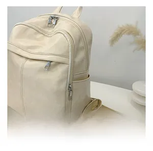Detail view of smooth zippers and storage pockets on beige faux leather backpack