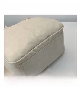 Detail view of smooth cream faux leather texture and reinforced double stitching on the backpack