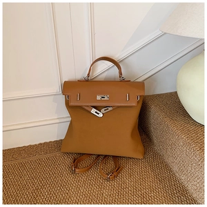 Detail of a brown leather Kelly style backpack with gold metal buckle on a woven rug