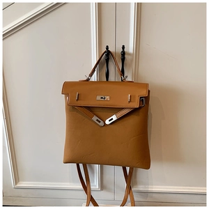 Detailed view of brown leather backpack with silver lock buckle and top handle