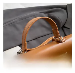 Detail shot of brown leather handbag handle and silver metal hardware lock mechanism