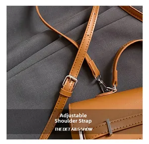 Detail showing the adjustable brown leather shoulder strap with silver metal buckle