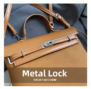 Detail of silver twist lock and horizontal straps on caramel brown leather handbag