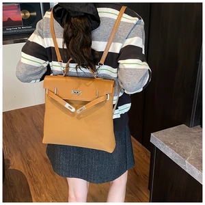 Detail shot of brown matte leather backpack featuring iconic metal turn-lock and flap