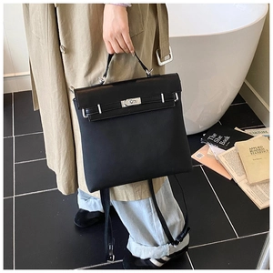 Detail of black textured leather bag with silver buckle held in a lifestyle setting