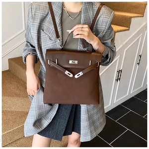 Brown matte leather backpack with silver twist lock shown on model in grey plaid suit
