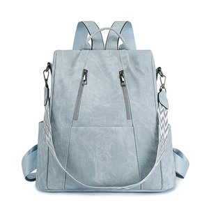 Detail of light blue-gray leather backpack showing litchi grain and dual front zippers