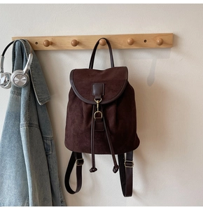 Detail of dark brown faux suede backpack featuring drawstring closure and metal hook buckle