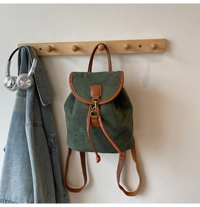 Detail of dark green frosted backpack with brown leather trim and metal hook closure