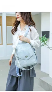 Outdoor shot of light blue canvas backpack with woven strap and metal buckle closure