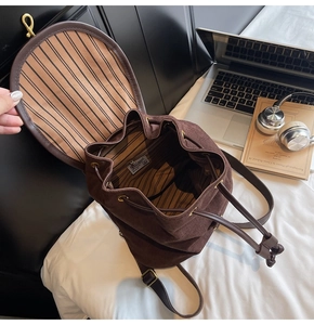 Detail view of large brown suede backpack with striped lining and drawstring closure