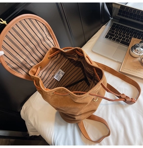 Close-up of brown drawstring backpack with striped lining and designer brand label