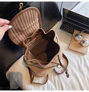 Detail view of large brown suede backpack with striped lining and drawstring closure