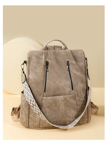 Detail of khaki vintage leather backpack with dual zippers and woven geometric strap