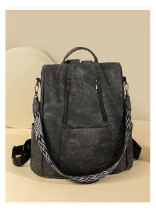 Close-up of charcoal gray backpack with ethnic pattern strap and dual vertical zippers