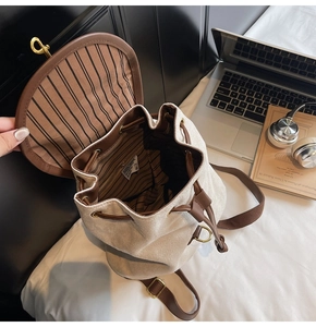 Detail of cream backpack showing striped interior lining with laptop and headphones