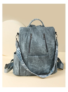 Detail view of washed blue backpack showing geometric patterned strap and vertical zippers