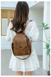Detail of soft brown leather backpack featuring vintage metal lock and ethnic woven strap