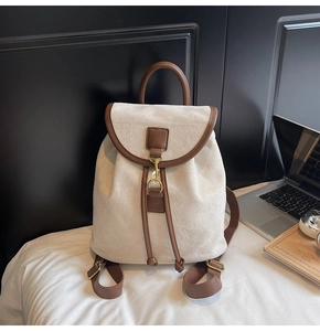 Detail of a matte cream backpack with brown leather trim and retro gold hook closure