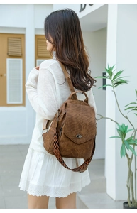 Detail of vintage brown textured leather backpack with geometric woven strap and twist lock