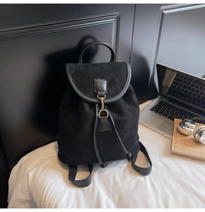 Close-up of black suede backpack with leather trim and gold hook closure detail