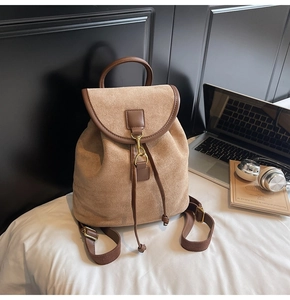Close-up of retro khaki suede backpack with brown leather trim and metal buckle details