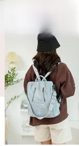 Detail of light blue textured backpack with woven strap and silver zipper on model