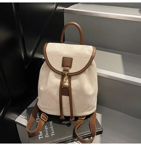Detail of retro cream backpack with brown leather trim and metal buckles on a book