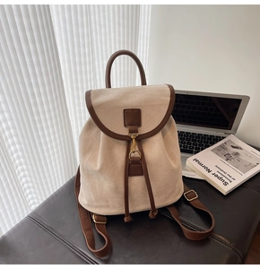 Detail of minimalist cream backpack with brown leather flap and vintage gold metal buckles