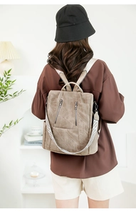 Detail of vintage brown leather backpack showing dual zippers and patterned shoulder strap