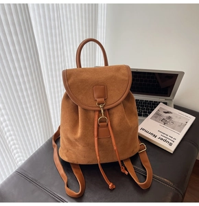 Detail of vintage brown suede backpack with metal buckle and drawstring closure