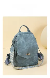 Detail of blue denim canvas backpack with textured strap and metal twist lock closure