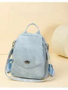 Close-up of light blue soft leather backpack with oval metal buckle and woven strap