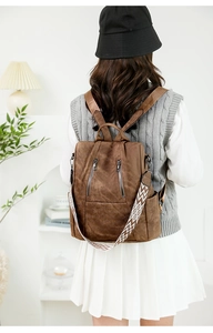 Detail of vintage brown leather backpack with geometric strap worn by female model