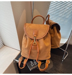 Detail of a brown suede backpack showing the metallic hook and drawstring closure