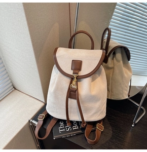 Detail of the vintage canvas backpack showing brown leather trim and metal hook closure